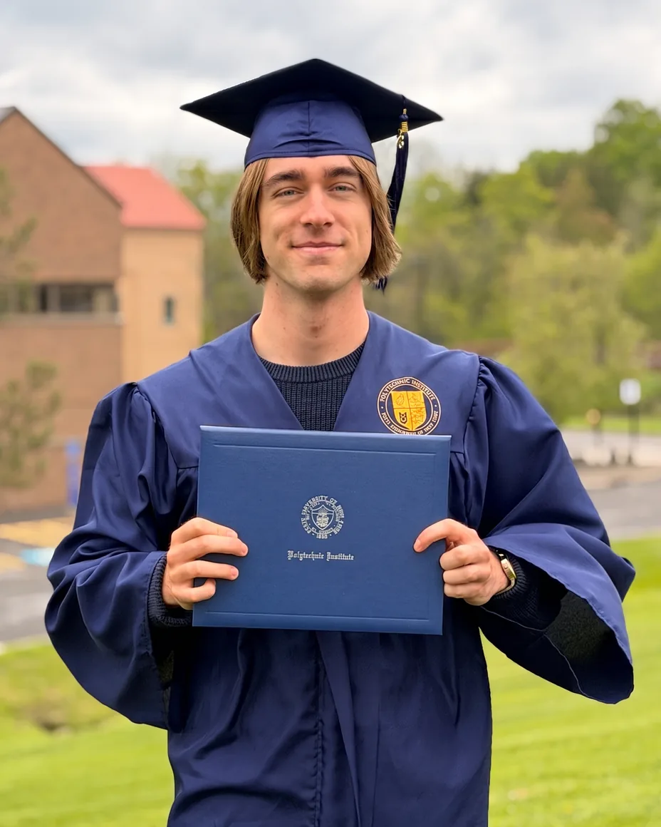 Gianni Luce, founder of Empire Designs, in cap and gown holding his SUNY Polytechnic Institute diploma